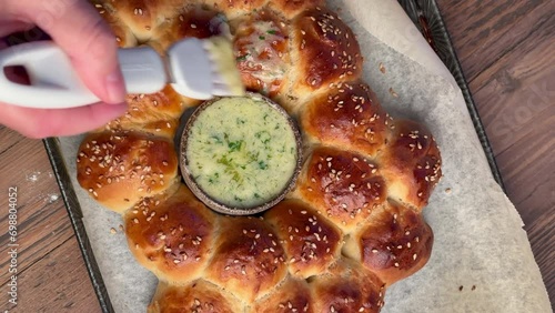 freshly baked yeast dough bread buns are smeared with melted butter with added chopped garlic and parsley. Baking pan on a wooden kitchen tabletop, top view photo