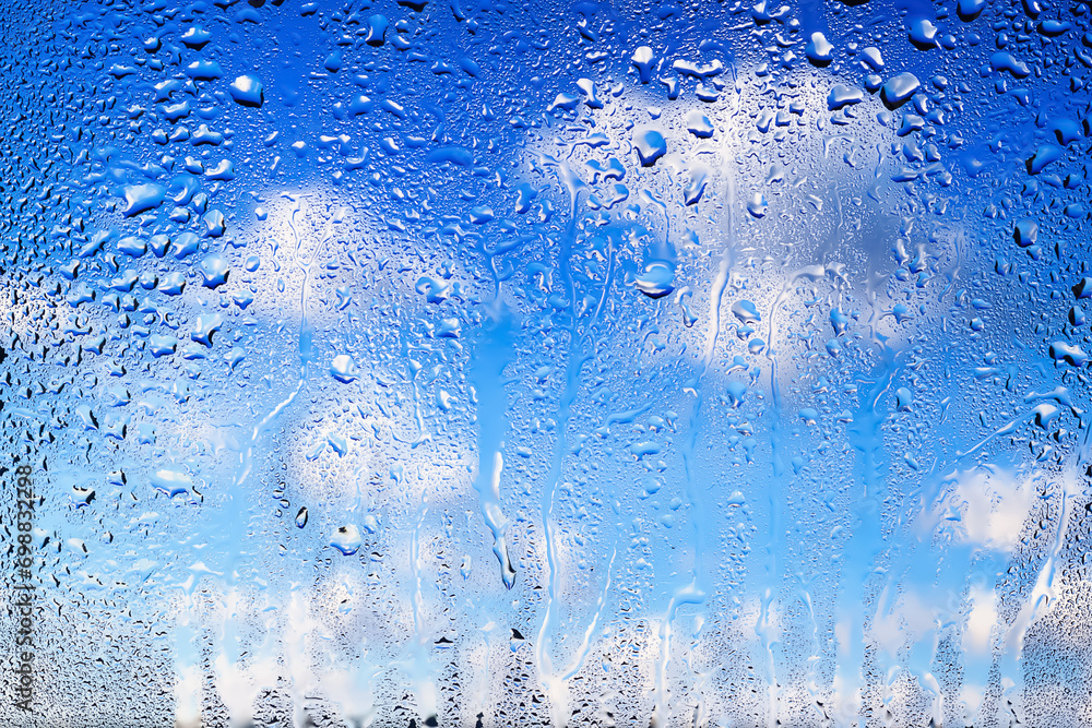 Drops of rain on the window. Water drops on glass. Abstract background. Blue sky with clouds. Texture of drops. Selective focus Drops of rain on the window. Water drops on glass. Abstract background. Blue sky with clouds. Texture of drops. Selective focus