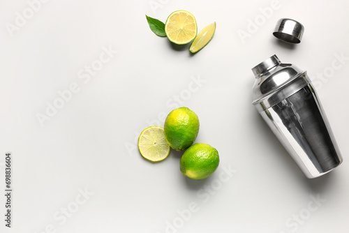 Shaker with fresh limes and leaves on grey background