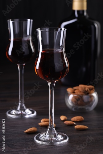 Liqueur glasses with tasty amaretto and almonds on wooden table, closeup