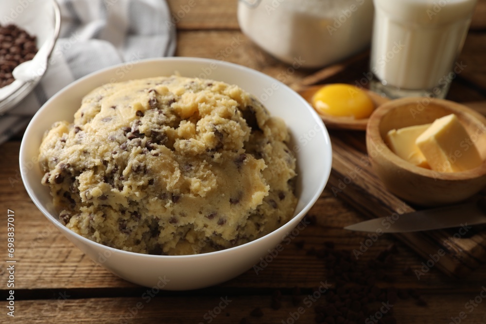 Chocolate chip cookie dough in bowl and ingredients on white wooden table, closeup Chocolate chip cookie dough in bowl and ingredients on white wooden table, closeup