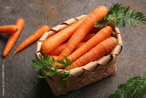 Wicker basket with fresh carrots on dark background
