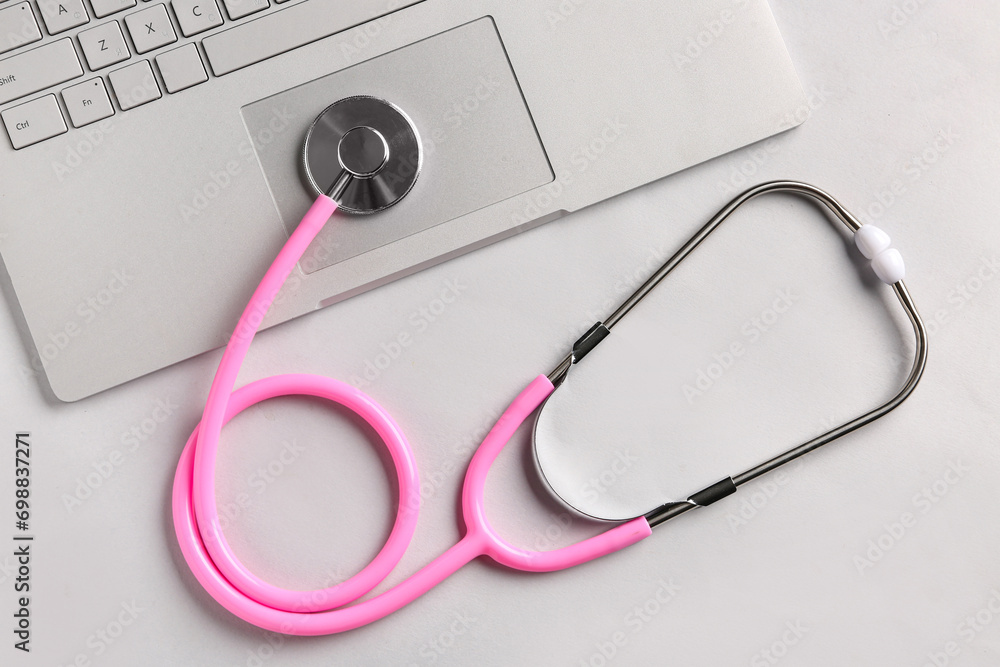 Stethoscope and laptop on light  background, top view