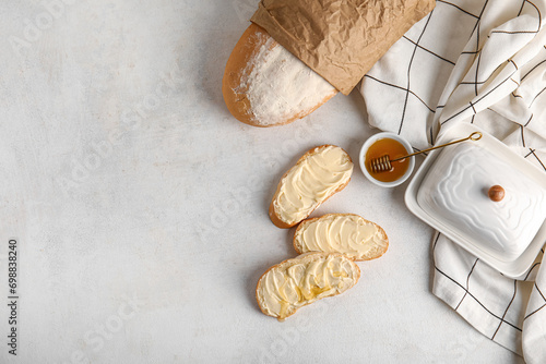 Tasty bread with butter and bowl of honey on white background