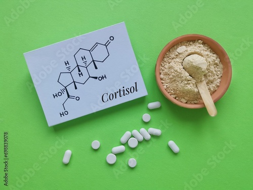 Structural chemical formula of cortisol (a steroid hormone) with white pills and ashwagandha powder. Cortisol is a stress hormone. Ashwagandha food supplements for stress and anxiety, medical concept photo