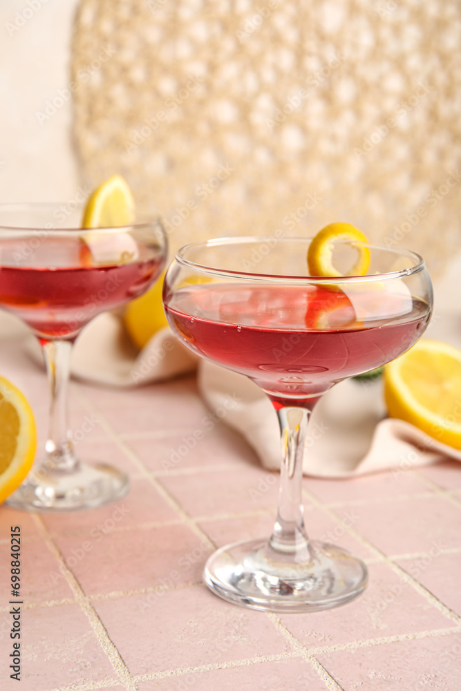 Glasses of Cosmopolitan cocktail with lemon on pink tile table
