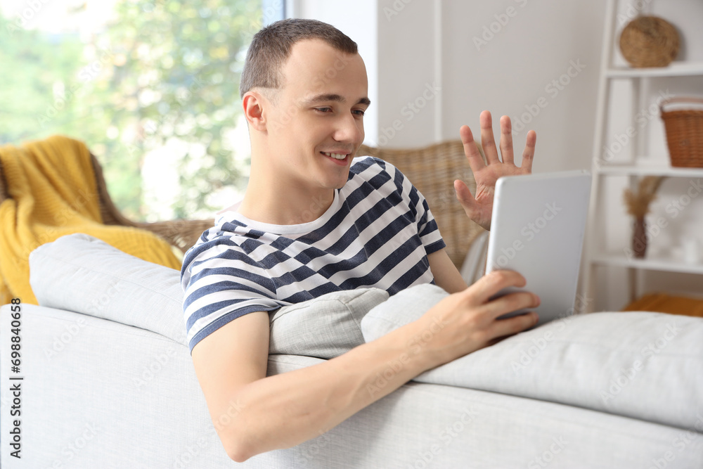 Young man using tablet computer on sofa at home Young man using tablet computer on sofa at home