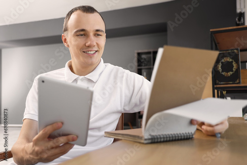 Young man working with tablet computer at table in office