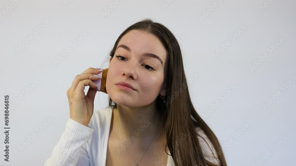 Attractive young woman doing her morning makeup with the brush in front of the mirror, white background Attractive young woman doing her morning makeup with the brush in front of the mirror, white background