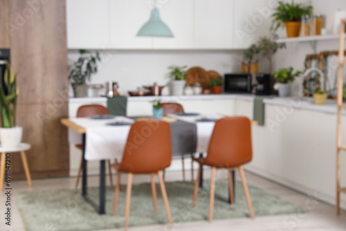 Blurred view of kitchen with green plants, dining table and counters