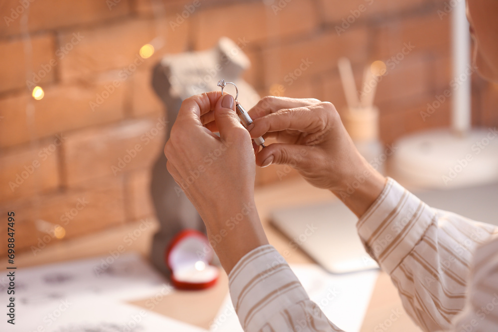 Female jeweler examining ring in workshop, closeup