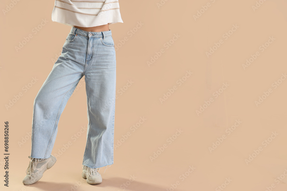 Young woman in trendy jeans on beige background Young woman in trendy jeans on beige background