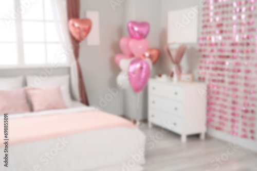 Blurred view of festive bedroom with heart-shaped balloons and cozy bed. Valentine s Day celebration