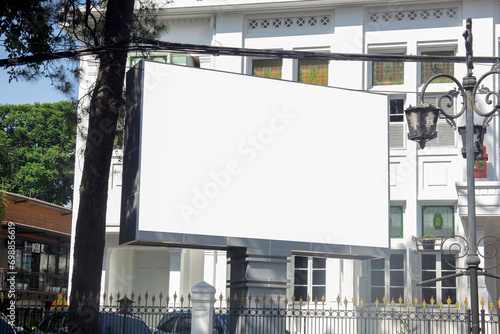 Large horizontal blank advertising poster billboard mockup in front of building in urban city