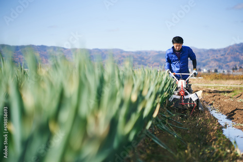 ネギの収穫のために耕運機で畑を耕す男性 photo