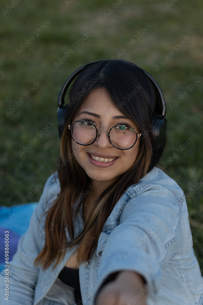Beauty woman with glasses takes selfie smiling in a nature park outdoors while wearing headphones