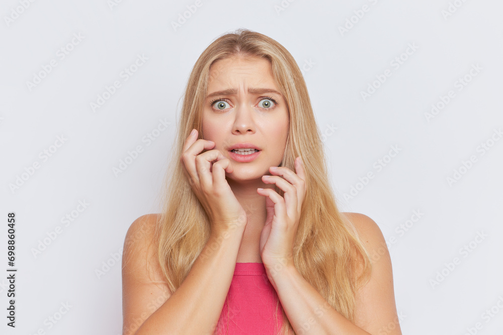 Young fair-haired woman with scared expression on face stands on white studio background, hard day concept, copy space Young fair-haired woman with scared expression on face stands on white studio background, hard day concept, copy space
