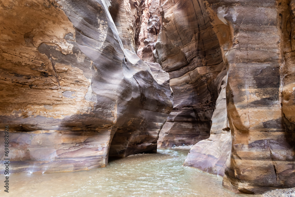 The shallow  Mujib River flows in canyon between high mountains along Mujib River Canyon Tourist Route in Wadi Al Mujib in Jordan