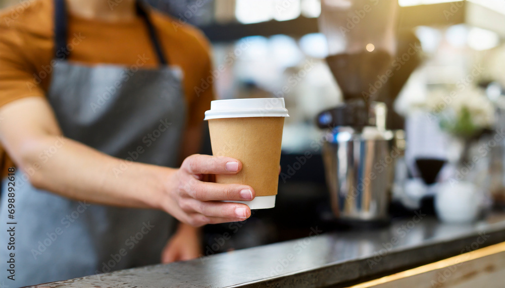 Barista holding paper cup of coffee in coffee shop, closeup