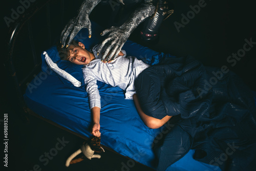 Scared boy in bed at night screaming while being attacked by a boogyman monster