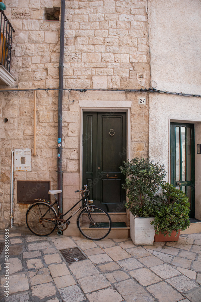 Bike parked near green door of old stone house in Polignano a Mare old town Bike parked near green door of old stone house in Polignano a Mare old town
