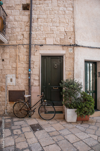 Bike parked near green door of old stone house in Polignano a Mare old town © Yurii Kushniruk