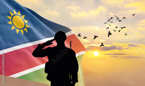Silhouette of a soldier with the Namibia flag stands against the background of a sunset or sunrise. Concept of national holidays. Commemoration Day.