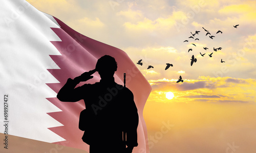 Silhouette of a soldier with the Qatar flag stands against the background of a sunset or sunrise. Concept of national holidays. Commemoration Day.