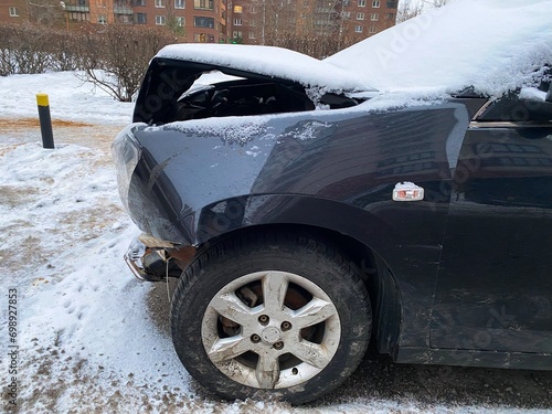 The front part of the car is damaged as a result of a traffic accident. The front part of the car is damaged as a result of the accident. The hood is bent, the headlight is broken, debris.
