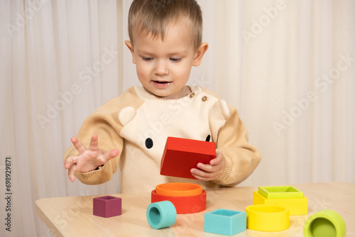 A two-year-old boy plays with wooden toys to develop logic and motor skills