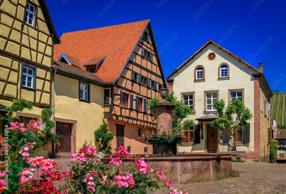 Traditional half timbered houses with blooming flowers in a popular village on the Alsatian Wine Route in Riquewihr, France