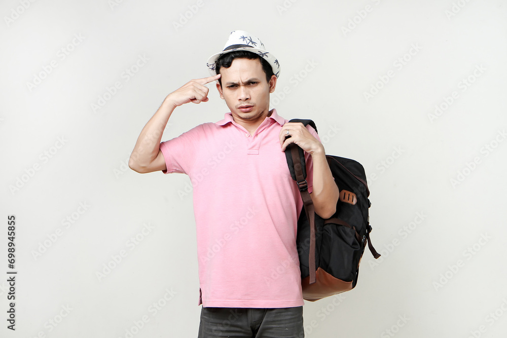 Asian man backpacker ponting finger on his head gesture. with confused, thinking, stressful expression. digital nomad and travelling concept. on isolated background Asian man backpacker ponting finger on his head gesture. with confused, thinking, stressful expression. digital nomad and travelling concept. on isolated background