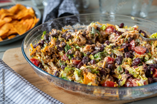 Tex mex taco salad with minded meat, kidney beans, cheddar cheese, romana salad, tomatoes and sour cream. photo