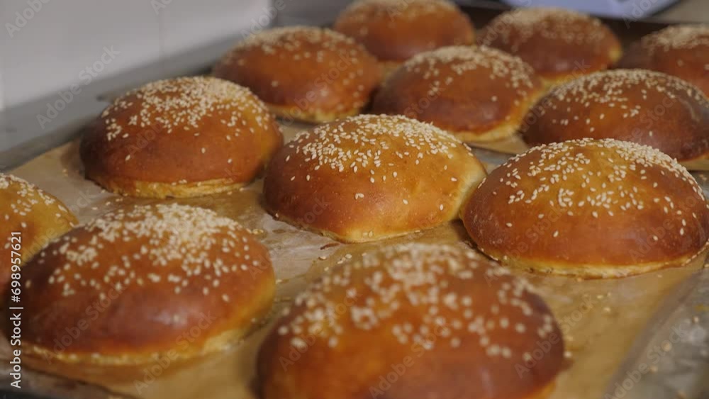 Close-up of freshly baked burger buns with sesame seeds in the restaurant kitchen. Fresh burger buns with a crispy crust. Close-up of freshly baked burger buns with sesame seeds in the restaurant kitchen. Fresh burger buns with a crispy crust.