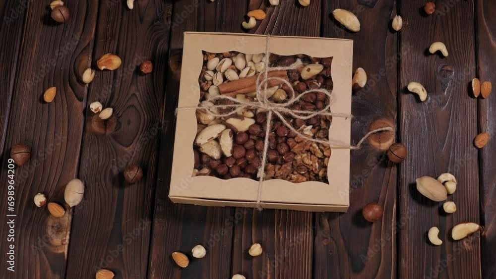 A gift set of various nuts in a gift box on a wooden surface. Various nuts are packaged in cells. View from above. A gift set of various nuts in a gift box on a wooden surface. Various nuts are packaged in cells. View from above.