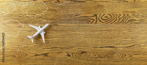 Creative white airplane and drawn clouds on wide wooden background with mock up place. 3D Rendering.