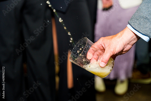 Hand holding a glass of cider at an event in a cider house, an alcoholic drink from the Basque country photo