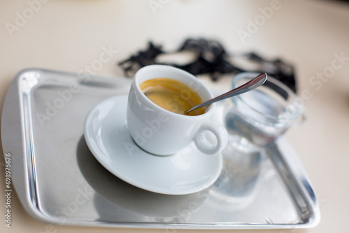 Fragrant coffee in a cup on a tray and water