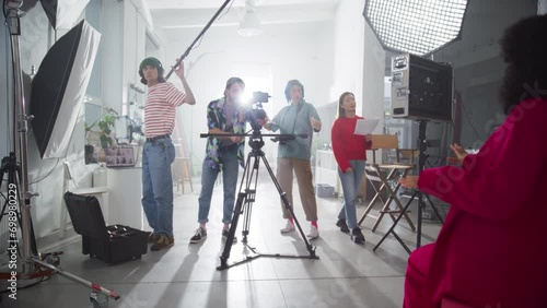 Behind the Scene Footage of a Commercial: Film Crew Working Together to Shoot an Aesthetic Video as Marketing Content. Dynamic Zoom Out Catching the Positive Energy of Young Video Creators photo