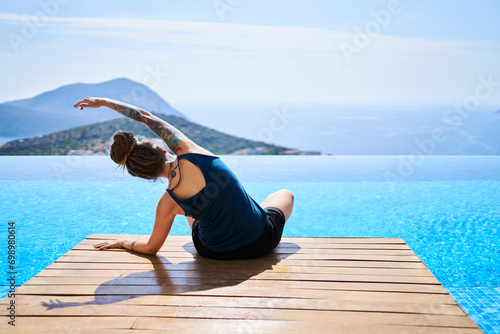 Woman doing stretching exercise near swimming pool photo