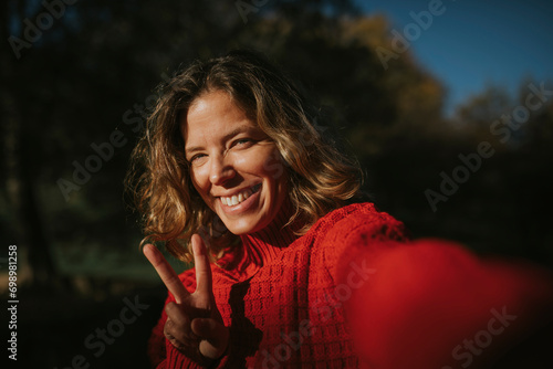 Smiling woman wearing red sweater and showing peace sign photo