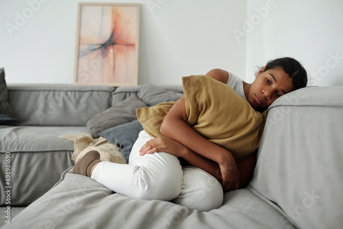 Depressed girl holding cushion and sitting on sofa at home photo