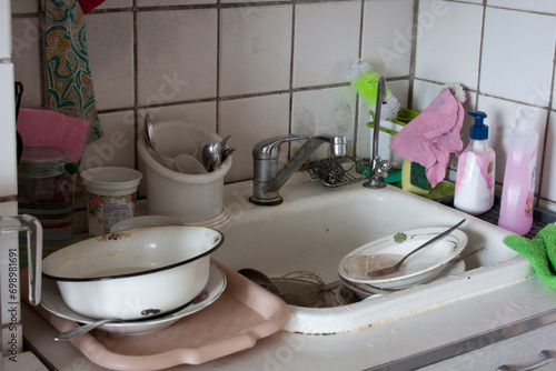 Fototapeta Naklejka Na Ścianę i Meble -  Dirty dishes in sink waiting to be washed. Dirty sink in apartment kitchen. Unsanitary conditions. Old dishes. Dirt everywhere. No water