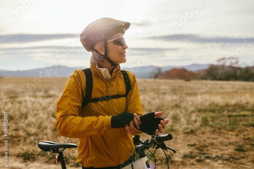 Smiling woman standing near mountain bike at field