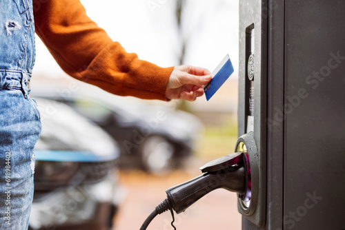 Woman paying with credit card at electric car charging station photo