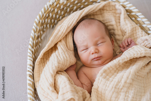 Newborn baby boy sleeping in moses basket photo