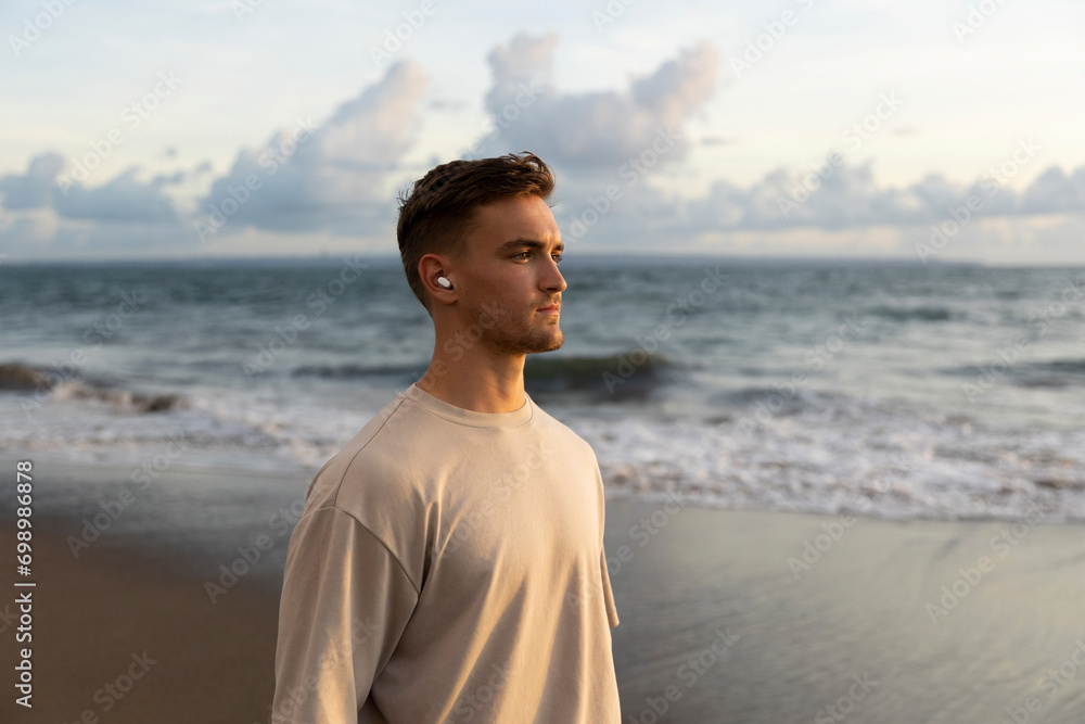 Young man wearing wireless in-ear headphones at beach Young man wearing wireless in-ear headphones at beach