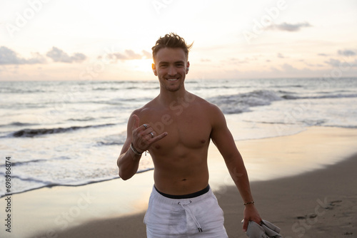 Happy young man gesturing Shaka sign at beach photo