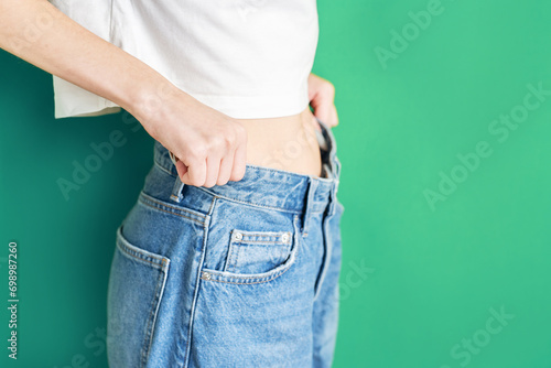 The girl is holding jeans that are too big. photo