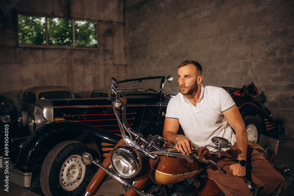 A man sits on a retro motorcycle in his garage